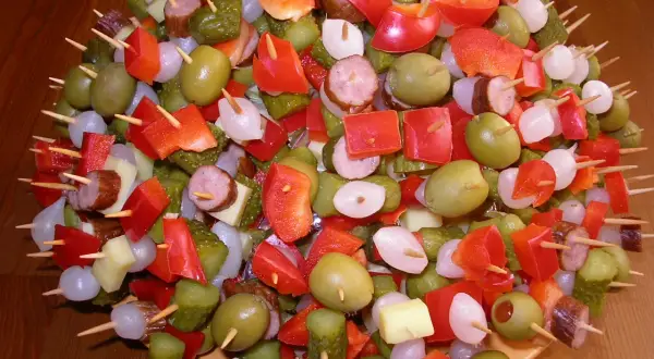 Kolorowe przekąski na andrzejki: oliwki, papryka, ogórki, ser i kiełbasa na wykałaczkach.