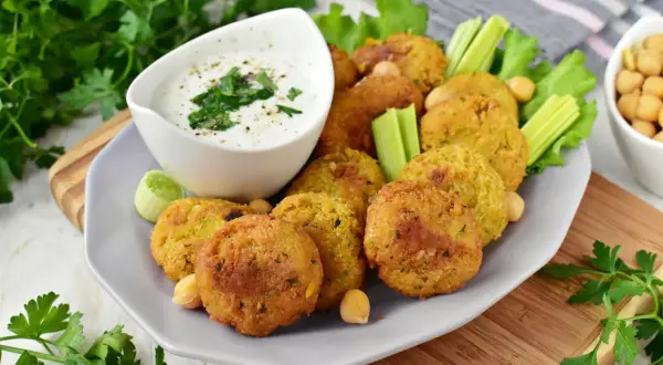 Chrupiące falafelki z ciecierzycy, podane z sosem jogurtowym i warzywami. Idealny falafel przepis na przekąskę.