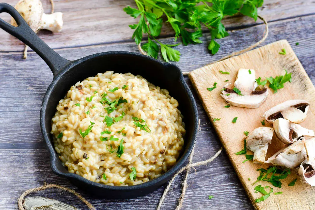 Kremowe risotto z grzybami, posypane natką pietruszki. Idealny przepis na pyszny obiad.