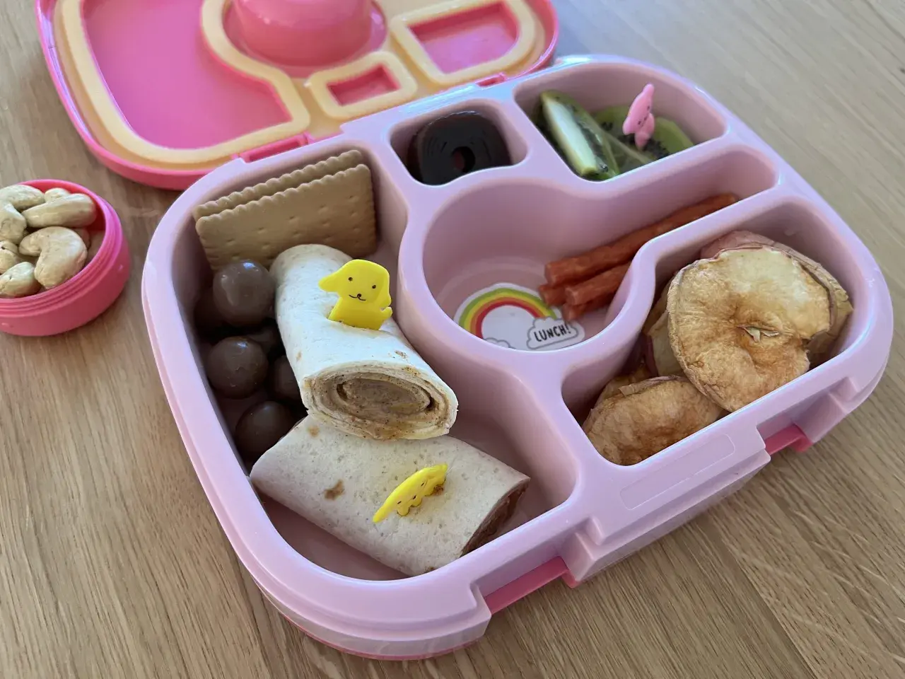 Kolorowe śniadanie dla 3 latka: wrap z żółtym pieskiem, ciasteczka, orzeszki, suszone jabłka, kiwi i czekoladowe kuleczki.