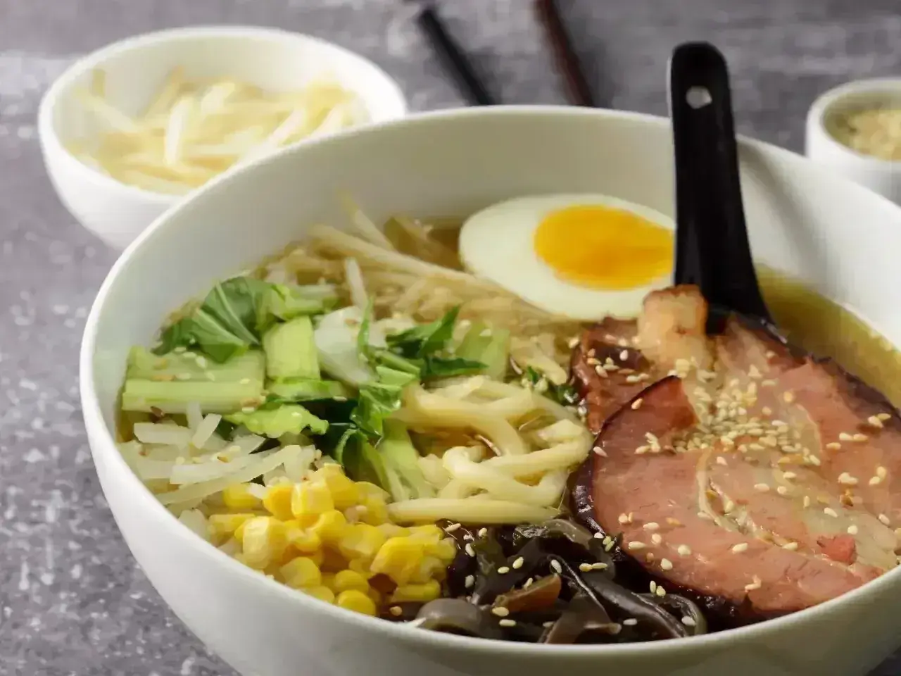 Pyszny ramen przepis: miska pełna makaronu, jajko na twardo, plastry boczku, warzywa i kiełki. Idealny na chłodne dni.
