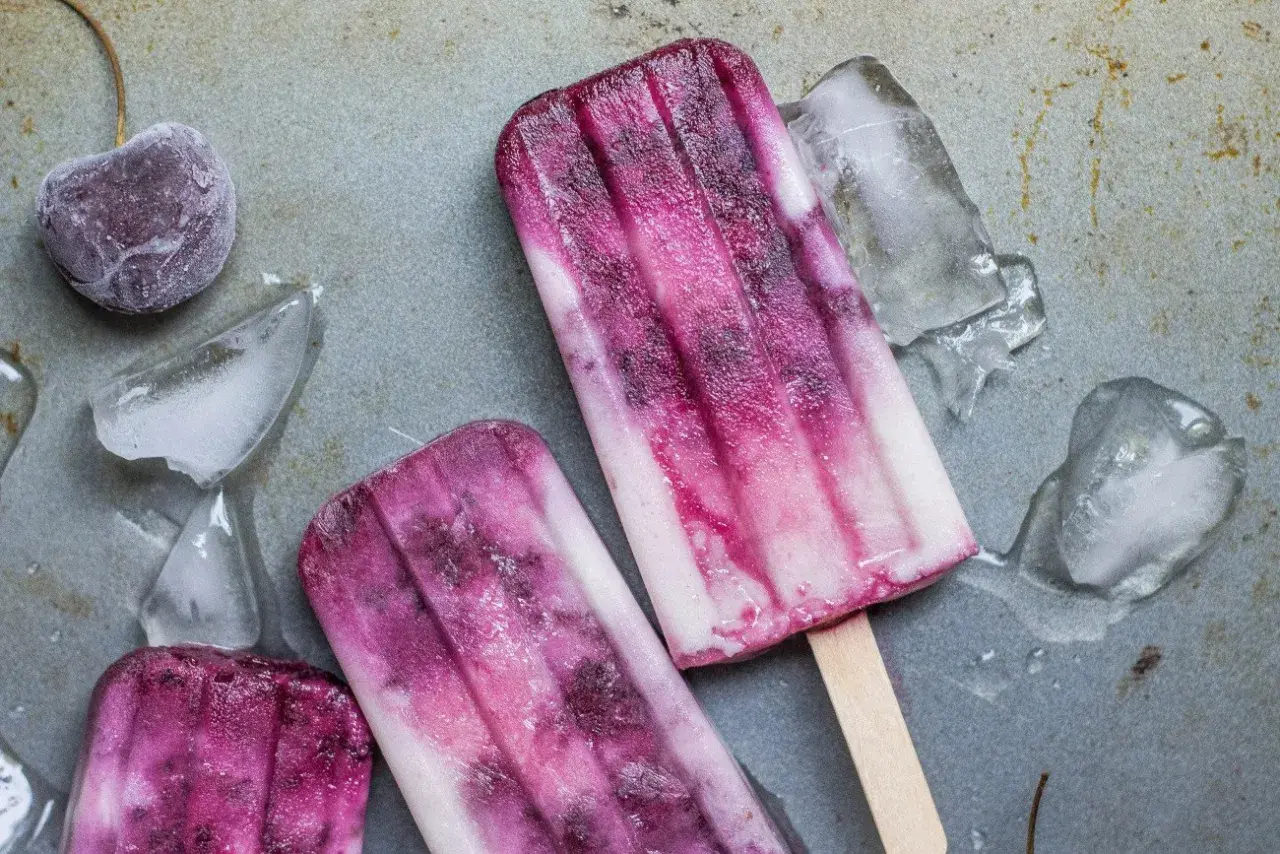 Dwa pyszne, domowe lody na patyku z wiśniami i kawałkami lodu.