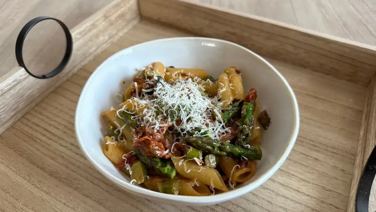 Penne z zielonymi szparagami i suszonymi pomidorami, posypane tartym parmezanem. Pyszne danie, które zachwyci każdego miłośnika makaronów.
