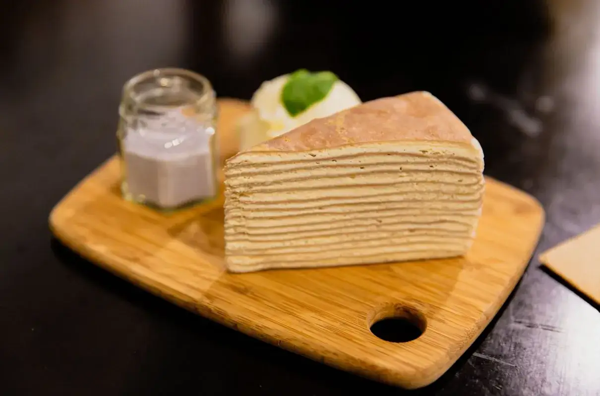 Kawałek mille-feuille, jeden z 10 najlepszych ciast, z lodami i sosem w słoiczku na desce.