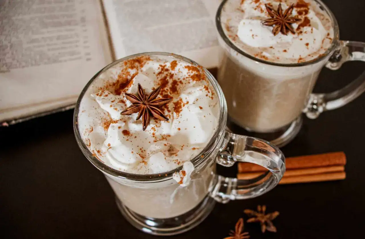 Dwa kubki aromatycznego chai latte z bitą śmietaną, cynamonem i anyżem. Idealne na chłodne popołudnie z książką.
