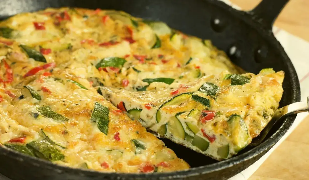 Pyszna frittata z cukinią i papryką, podana w żeliwnej patelni, gotowa do podania.