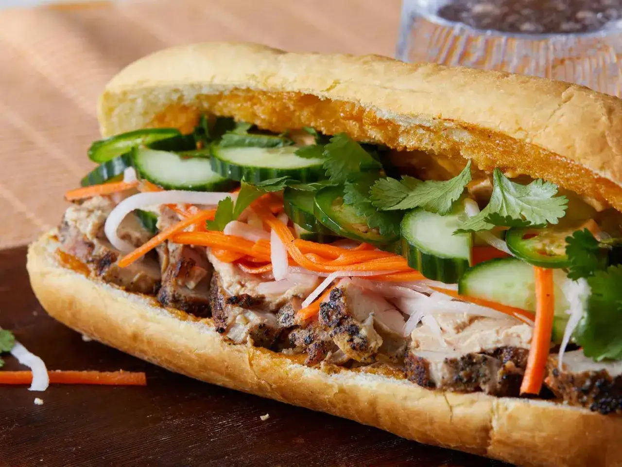 Pyszny banh mi przepis: chrupiąca bagietka z grillowaną wieprzowiną, marynowaną marchewką, ogórkiem, kolendrą i jalapeño.