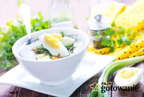 Aromaticzna zupa koperkowa z jajkiem i zieloną cebulką, podana w białej miseczce na drewnianym stole.