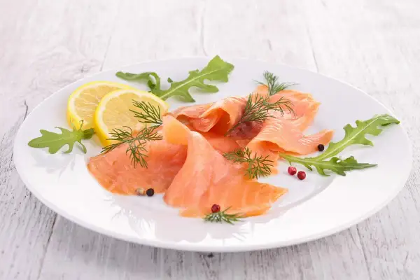 Eleganckie carpaccio z łososia, ozdobione rukolą, cytryną i koperkiem, kusi delikatnym smakiem.