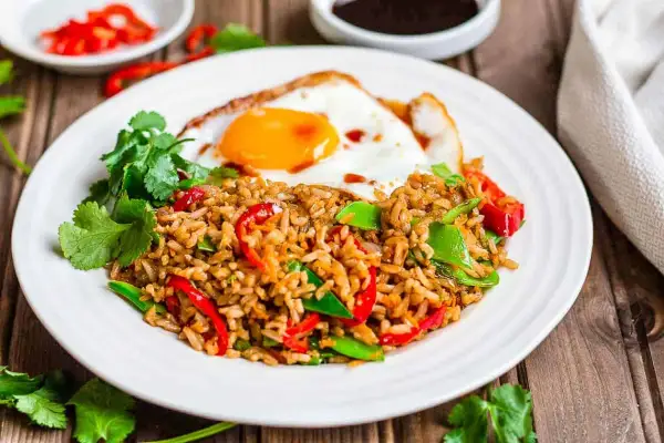 Nasi goreng z jajkiem sadzonym, papryką i zielonym groszkiem, ozdobione kolendrą. Pyszne danie, które rozgrzeje każde podniebienie.