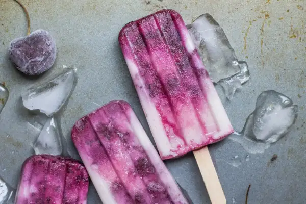 Dwa pyszne, domowe lody na patyku z wiśniami i kawałkami lodu.