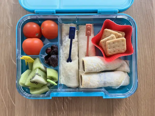 Kolorowe kanapki dla dzieci w pudełku: naleśniki z czekoladą, kiwi, pomidorki i ciasteczka.