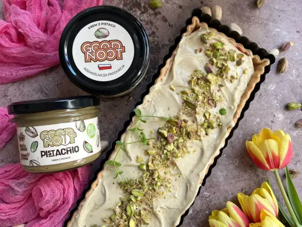 Nowoczesny mazurek wielkanocny z kremem pistacjowym. Idealny na święta, udekorowany pistacjami i gałązką mięty.