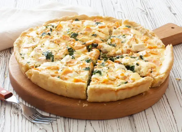 Pyszna tarta z łososiem, szpinakiem i serem feta, pokrojona na kawałki, gotowa do podania.
