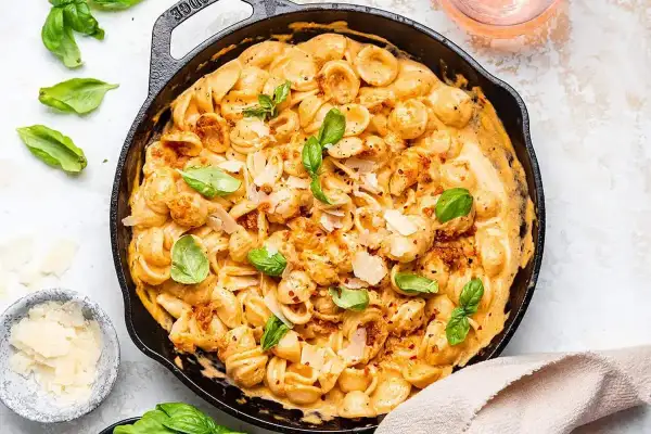 Orecchiette w kremowym sosie z suszonych pomidorów, posypane parmezanem i świeżą bazylią. Pyszne danie, które zachwyci każdego.